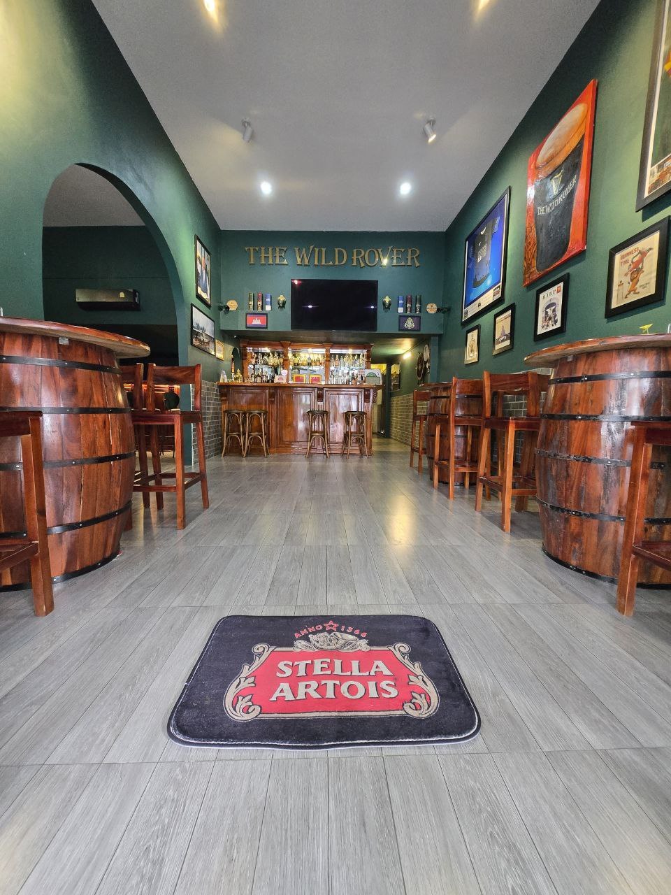 Barrel furniture, wooden bar, and framed artwork inside The Wild Rover Irish Pub Phnom Penh